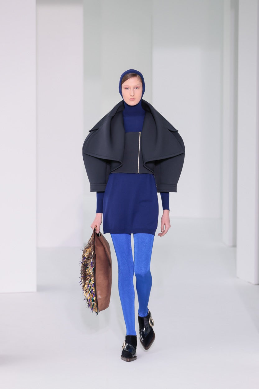 Vestido de punto azul Klein con capucha y chaqueta en lana azul marino con solapa 'oversize', combinado con medias azules, botín en piel efecto potro azul y spazzolato burdeos y bolso Moon en piel efecto potro tofe con bordado multicolor.