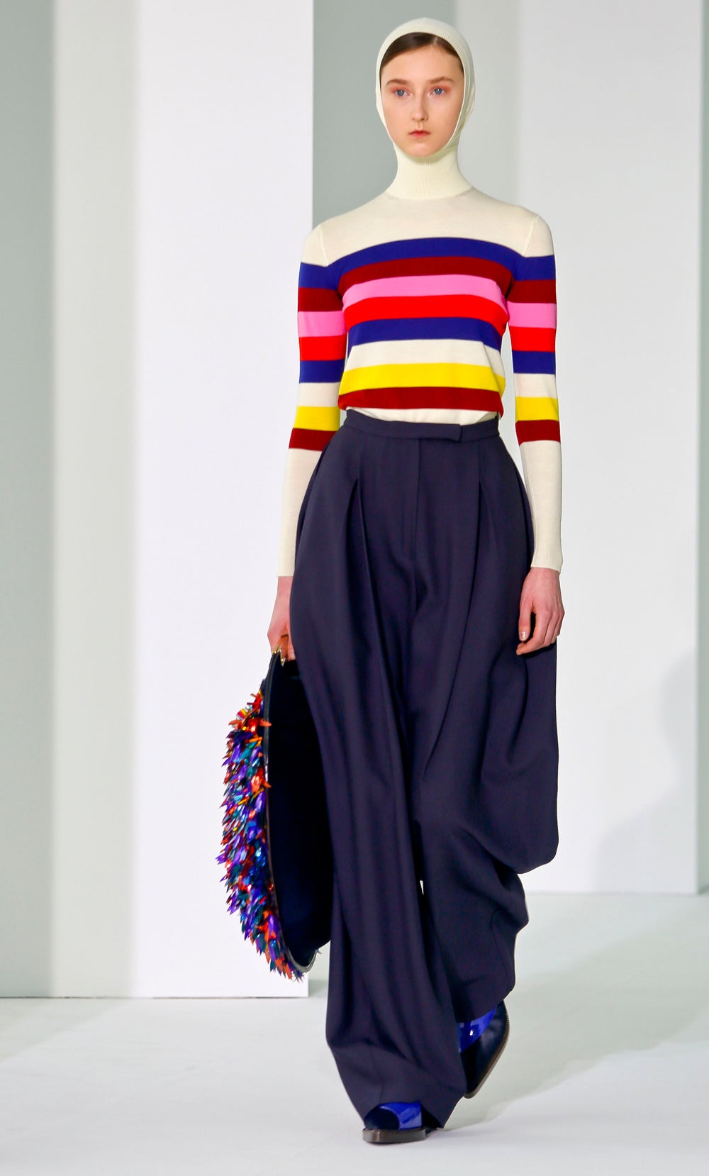 Font añade capucha a sus jerseys de punto, en este caso un modelo con estampado de rayas que combina con un pantalón palazzo azul noche, botines planos y maxi bolso con bordado multicolor.