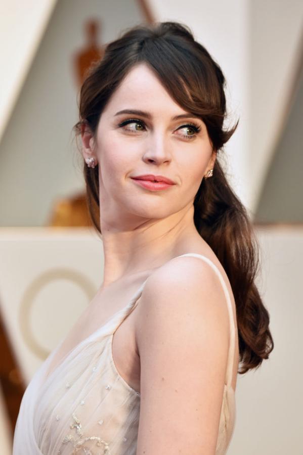 Felicity Jones, muy guapa, con un semirrecogido con ondas que combinó con eyeliner negro marcado, pestañas XXL y labios nude.
