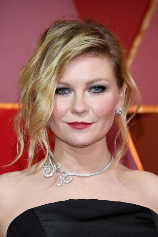 La actriz Kristen Dunst con un recogido con acabado messy y mechones sueltos, que combinó con labios rojos mates y ojos enmarcados en eyeliner negro y sombras grises.
