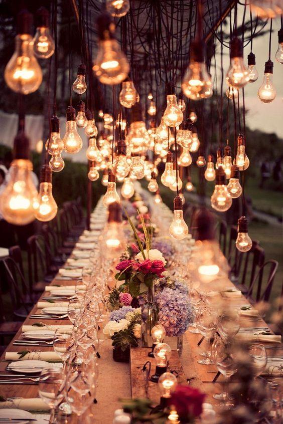 La luz juega un papel fundamental en la decoración de las bodas al aire libre, así que apuesta por un aire 'rustic chic' con detalles vintage, como las mesas de madera con flores naturales y estas impresionantes bombillas retro como protagonistas (Foto: Pinterest).