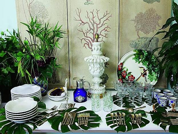 Mesa auxiliar, la vajilla y los cubiertos, sobre hojas de costilla de Adán.