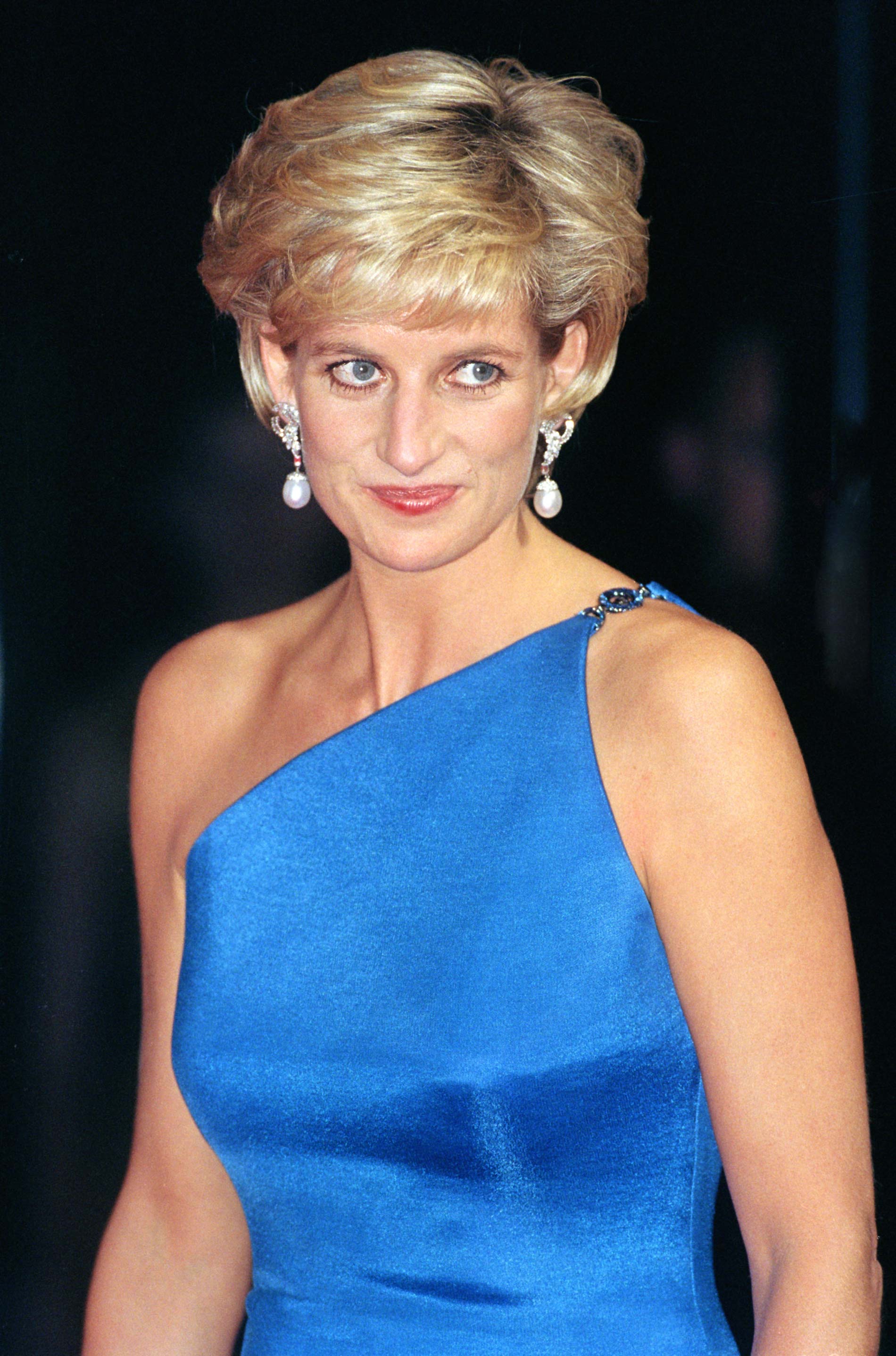Diana de Gales con un vestido azul de tirantes y unos pendientes de perla largos.
