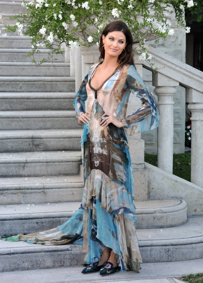 Alberta Ferretti también firma este vestido de gasa estampada con volantes y amplio escote que Isabeli Fontana combina con unos mules con 'print' floral.