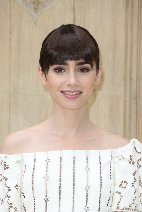 Lily Collins lleva flequillo tupido recto, con los extremos un poco más largos, con moño de bailarina.