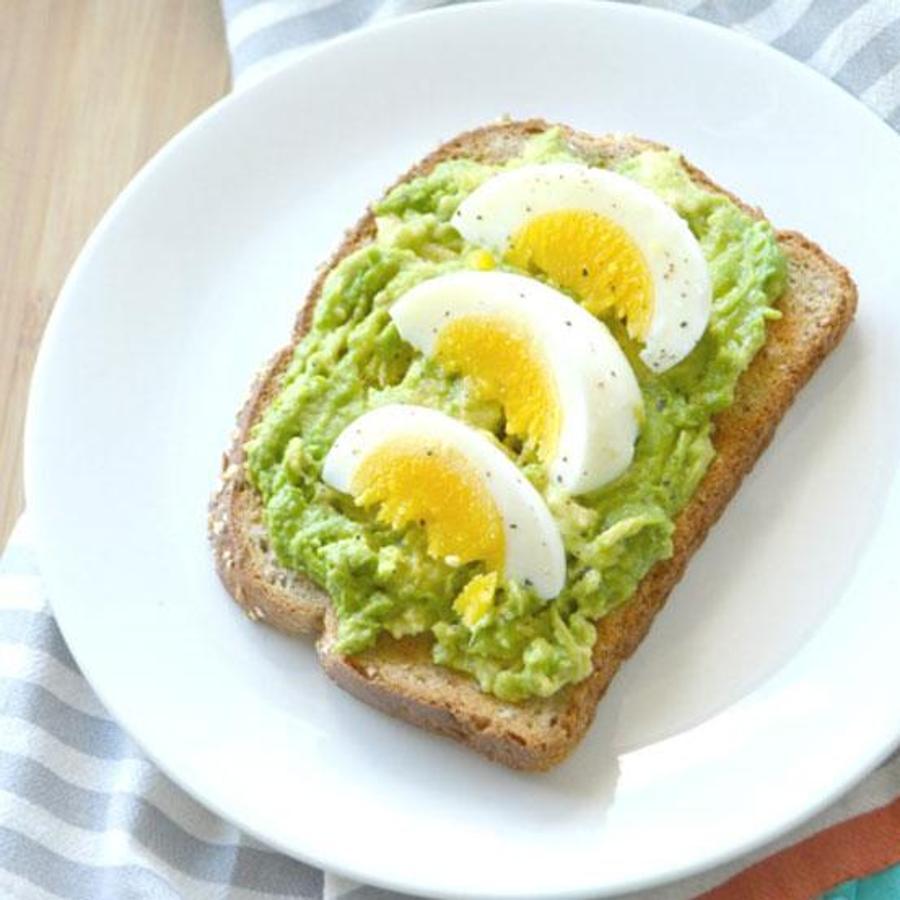 Elabora un paté de aguacate con gotas de limón y aceite de oliva virgen extra, úntalo sobre una tostada integral y coloca unas rodajas de huevo cocido con perejil por encima.