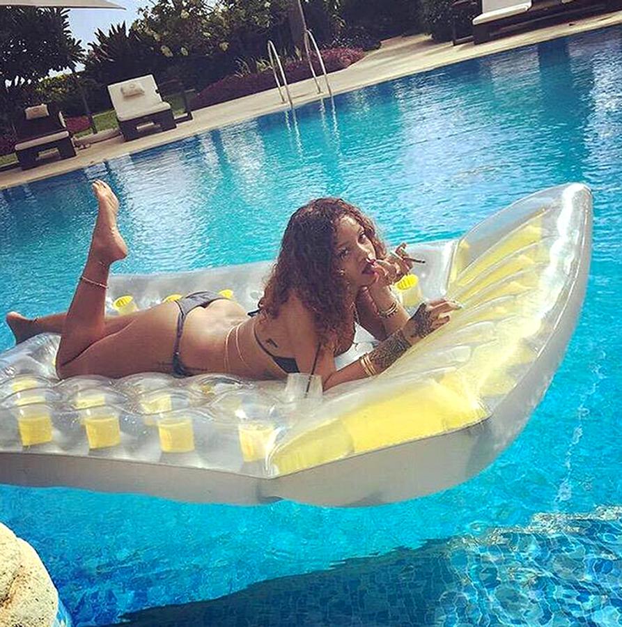 Una típica instantánea de Rihanna durante sus vacaciones: bikini escueto, curvas de infarto, cóctel en una mano y cigarrillo en la otra...