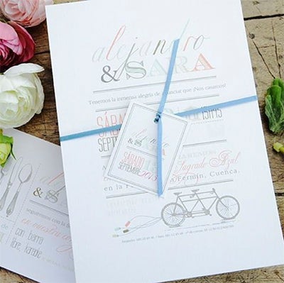 Un juego de tipografías, letterpress. Invitación de boda en forma de díptico vertical con un lazo fucsia a conjunto.