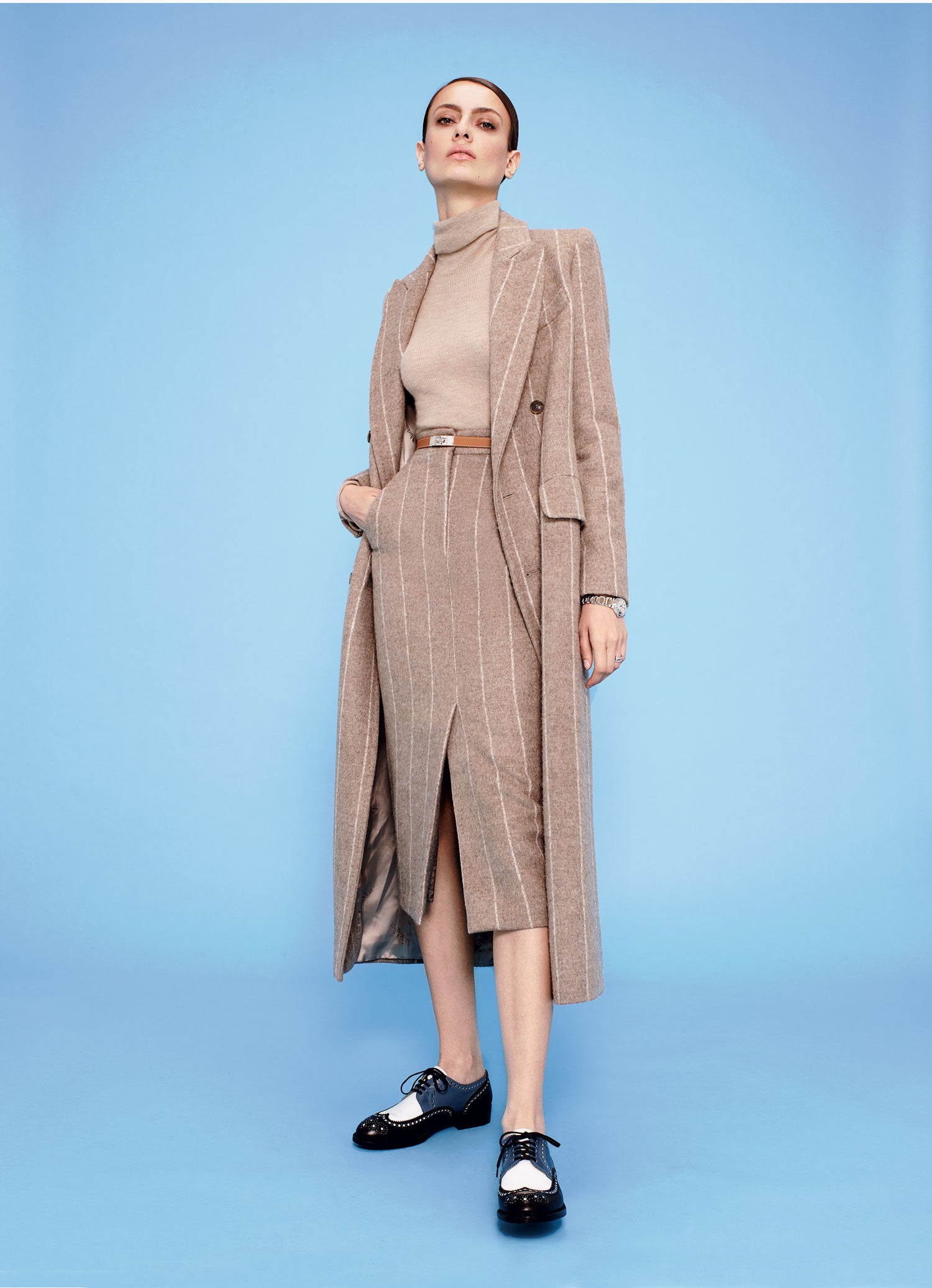 Abrigo, falda y jersey de cuello cisne, todo de Max Mara. El cinturón es de Hermés y los zapatos, de Robert Clergerie. El reloj y el anillo son de Cartier.