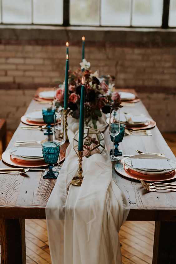 ¡Por todo lo alto! Tus invitados no lo podrán olvidar. Cualquiera se queda boquiabierto si ve una mesa como esta. Sin mantel, pero con una tela a lo largo de la misma que carga las flores y velas que decoran el centro. Los platos, todos con una dedicatoria, menú o villancico y con tonalidades combinadas que varían entre el blanco y el dorado. ¡Único y especial! Ya sabes, ¡imagina y crea!