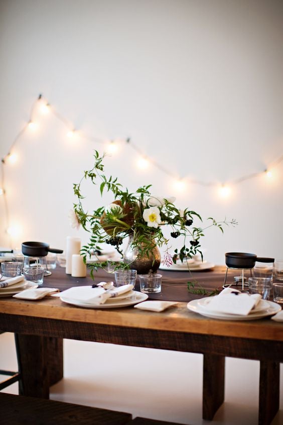 En lugares más íntimos, y cenas más sencillas podemos utilizar una decoración simplista pero no ausente en detalles. En esta imagen se observa un conjunto de cubertería plateada y vajilla blanca, que resalta la pureza de los días más emocionantes del año. Por su parte, para dar un toque más personal, colocar un centro de mesa con motivos florales que rompa con la monocromía de la mesa.