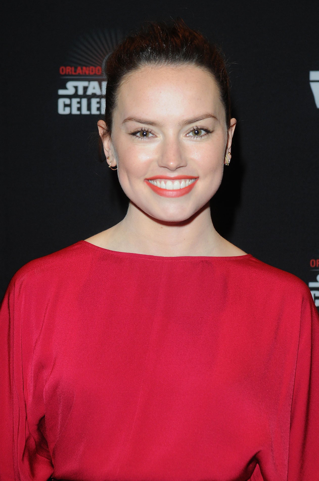 Para el día o la noche, elige un labial naranja o rojo claro y combínalo con un toque de colorete melocotón y máscara de pestañas como Daisy Ridley.