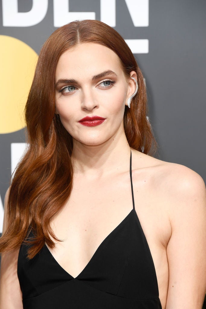 Madeline Brewer con melena suelta con ondas abiertas y labios rojos difuminados.