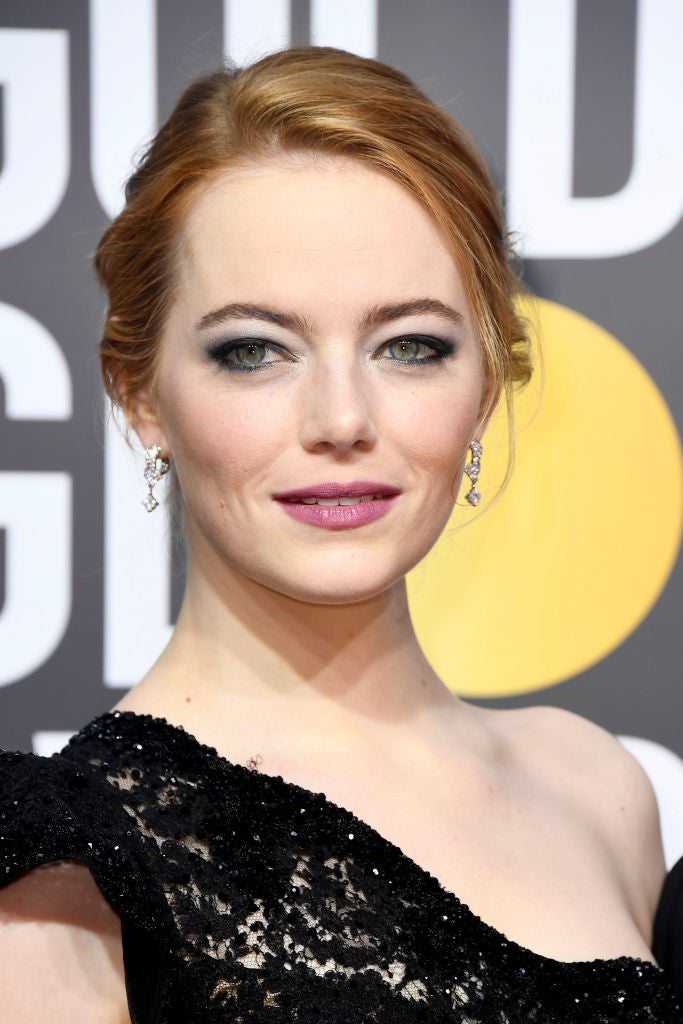 Emma Stone con recogido clásico, sombras azules y labios rosas en la alfombra roja de los Globos de Oro 2018.