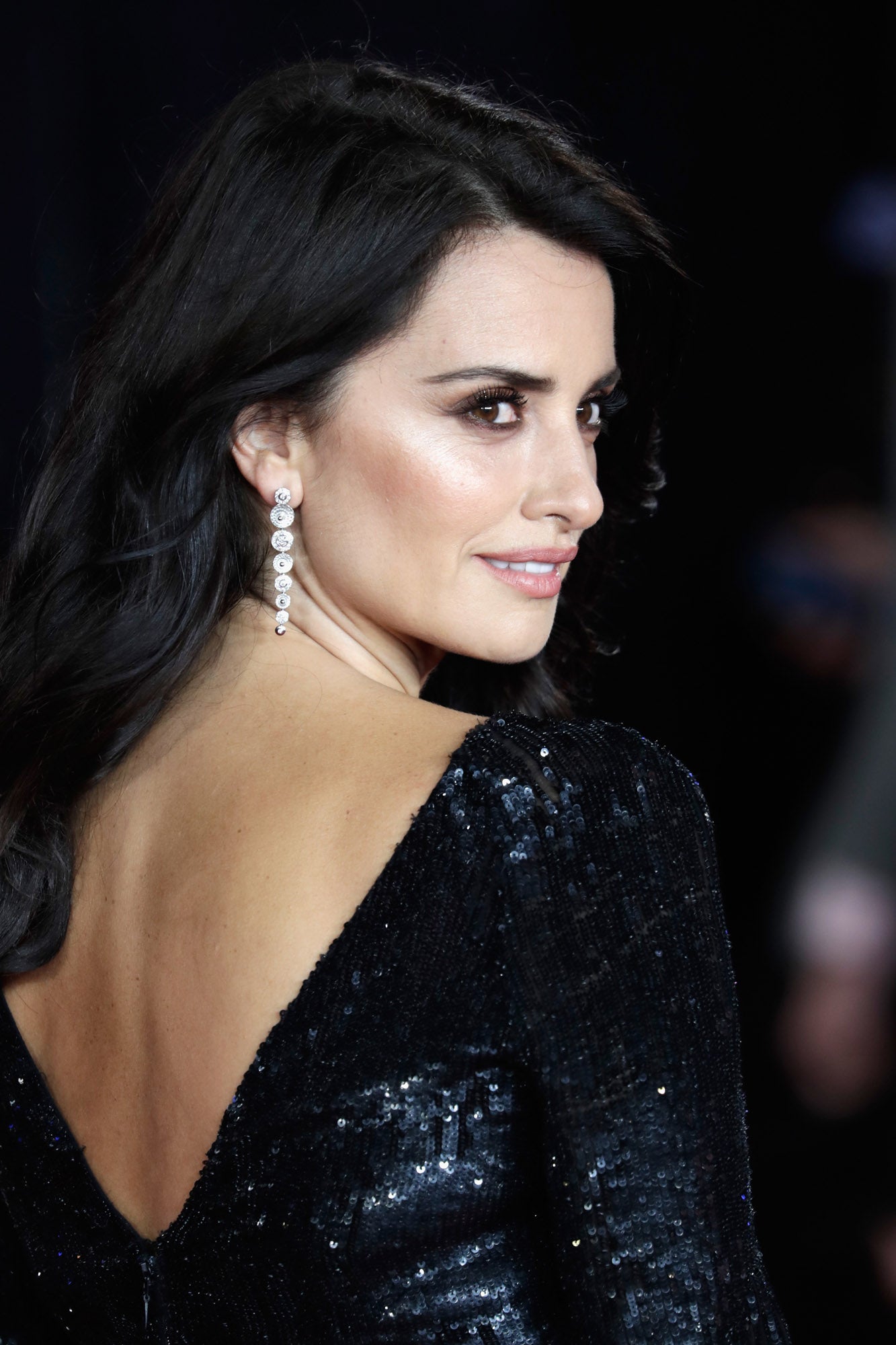 Penélope Cruz con los labios rosas empolvados que contrastan con su mirada felina y su vestido oscuro.