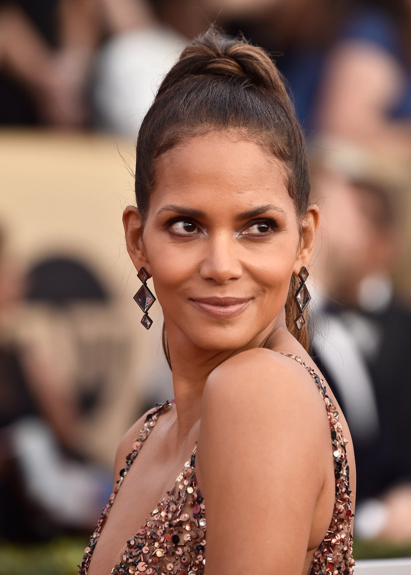 Halle Berry recogió su melena en una coleta alta envuelta y partida a la altura de la nuca. En su maquillaje destacan las sombras glitter, muy luminosas.