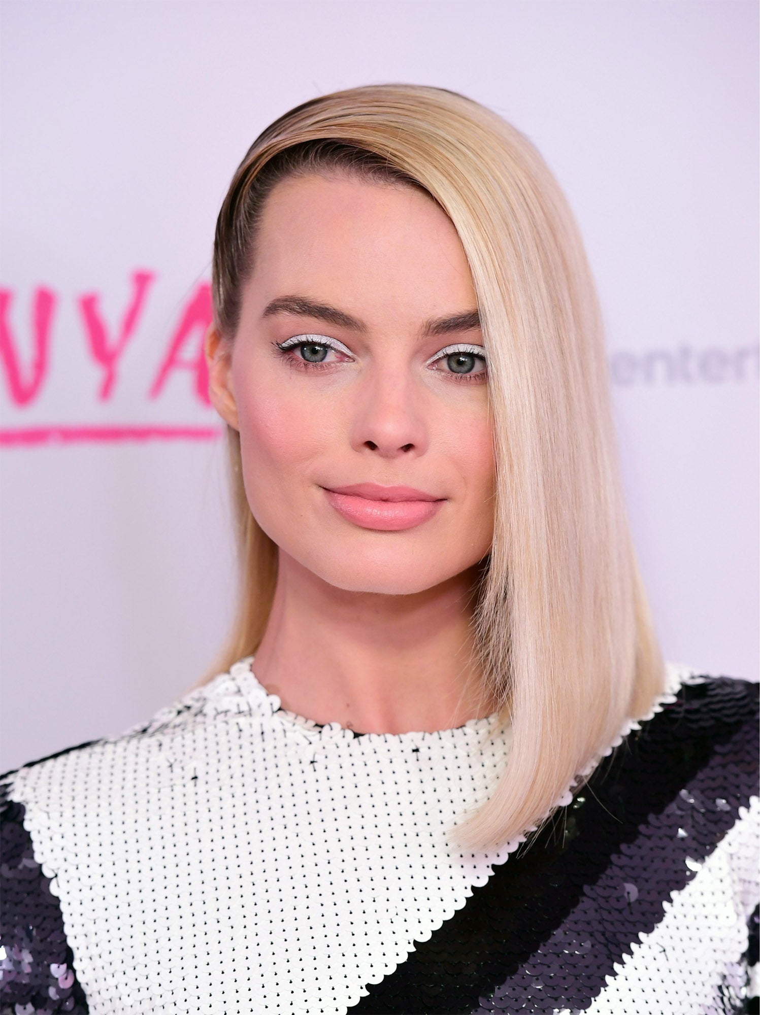 Margot Robbie con su media melena muy lisa y peinada completamente hacia un lado muy pulida en las raíces.