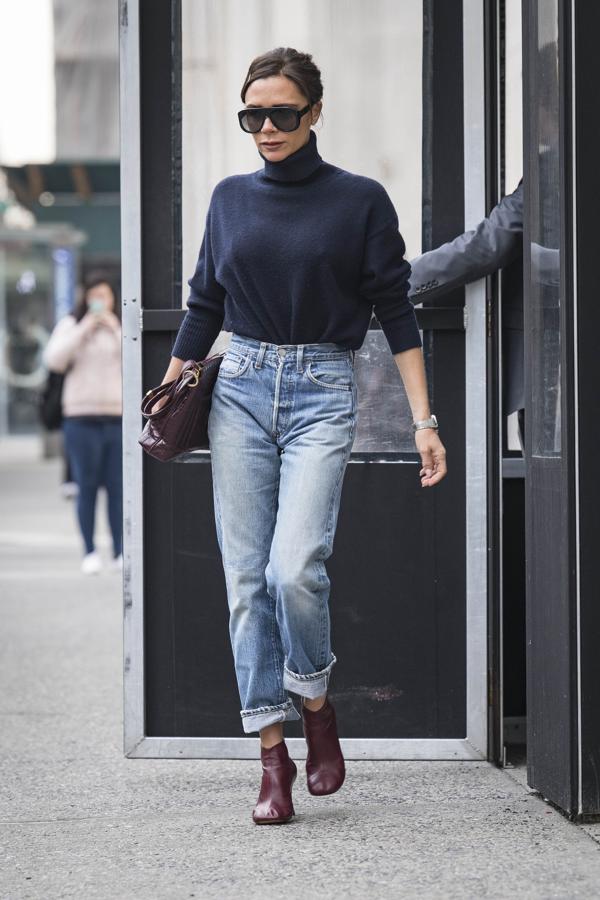 Menos es más y así lo demuestra Victoria Beckham con unos jeans de talle alto y jersey de cuello alto. En los pies, unos botines de piel con la puntera redonda y bolso granate a juego