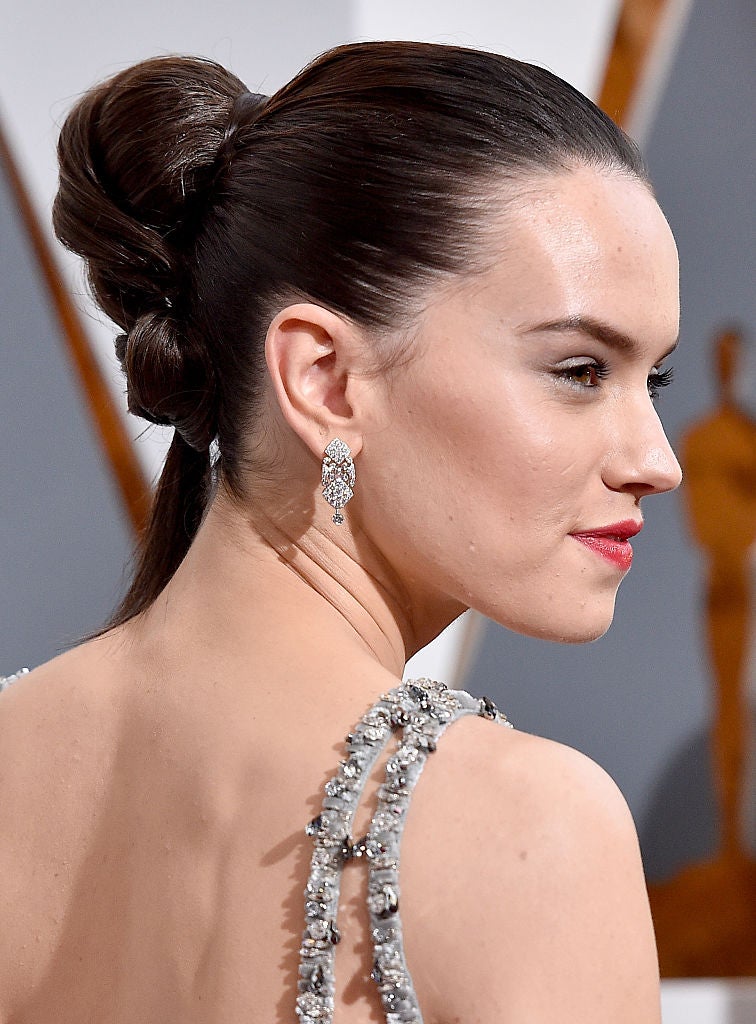 Daisy Ridley lució un original peinado en los Oscar 2016, un moño que acababa en coleta, y que combinó con labios rojos.