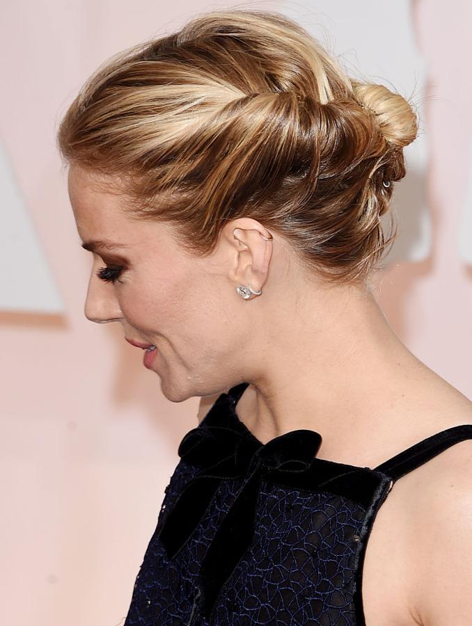 Siena Miller con moño y mechones retorcidos en los Oscar 2015. El maquillaje brilló con sus ojos ahumados en marrón chocolate.