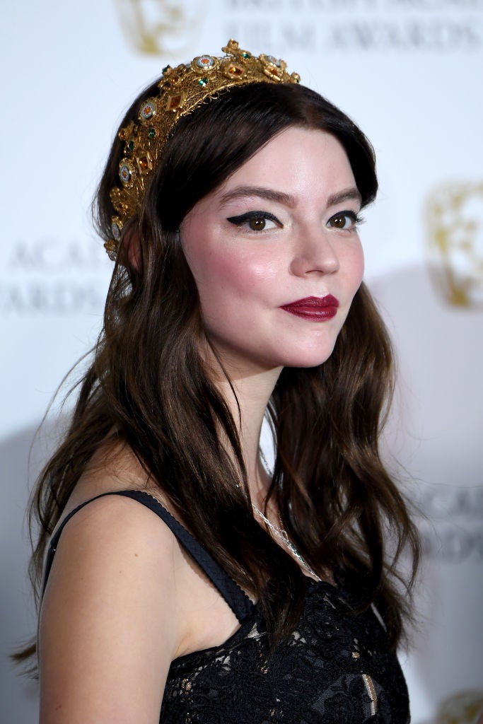 Anya Taylor Joy lució su melena suelta con ondas rotas y adornada con una diadema barroca. Como maquillaje, eyeline negro con rabillo y labios rojos.
