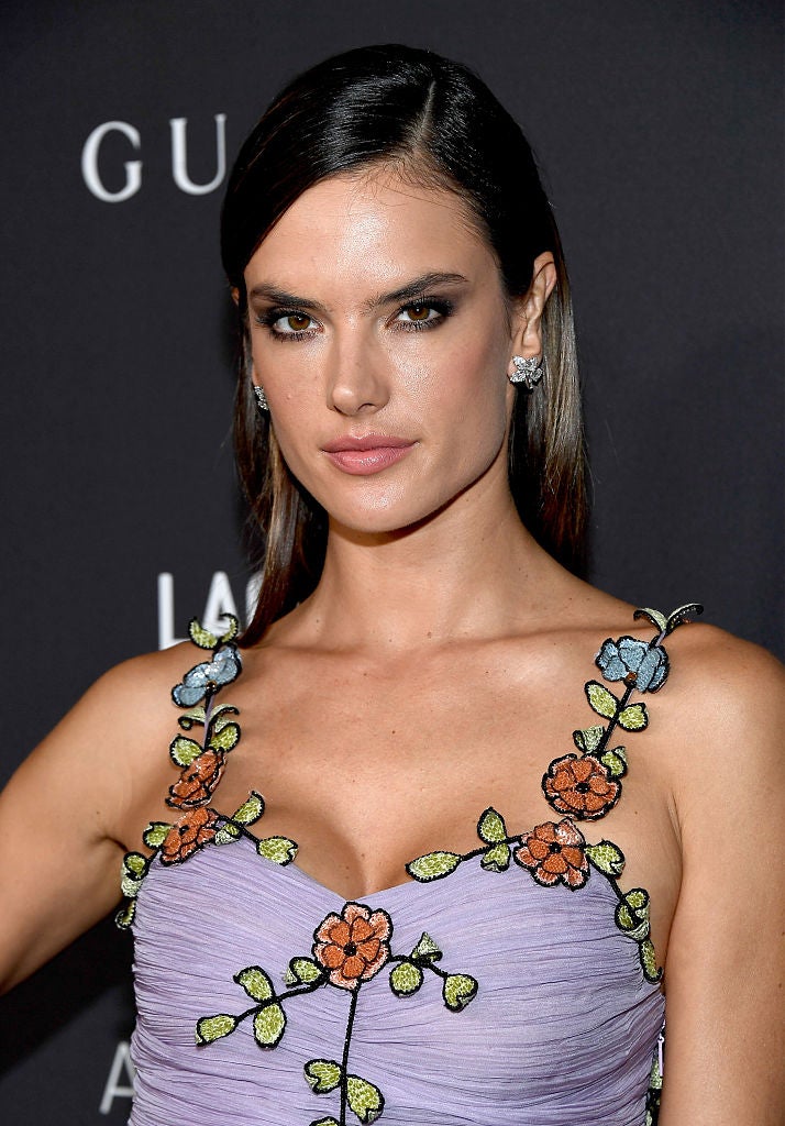 Alessandra Ambrosio con el pelo liso largo, peinado con raya a un lado y escondido detrás de la oreja.