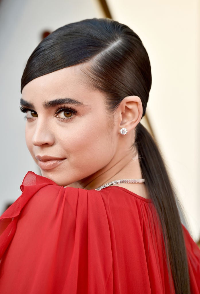 La coleta es uno de los peinados más sencillos, lo puedes hacer tú misma y es perfecto para una boda. Busca, eso sí, una coleta especial como la de Sofia Carson. Con el pelo muy pulido liso, raya lateral baja y recogida a la altura de la nuca.
