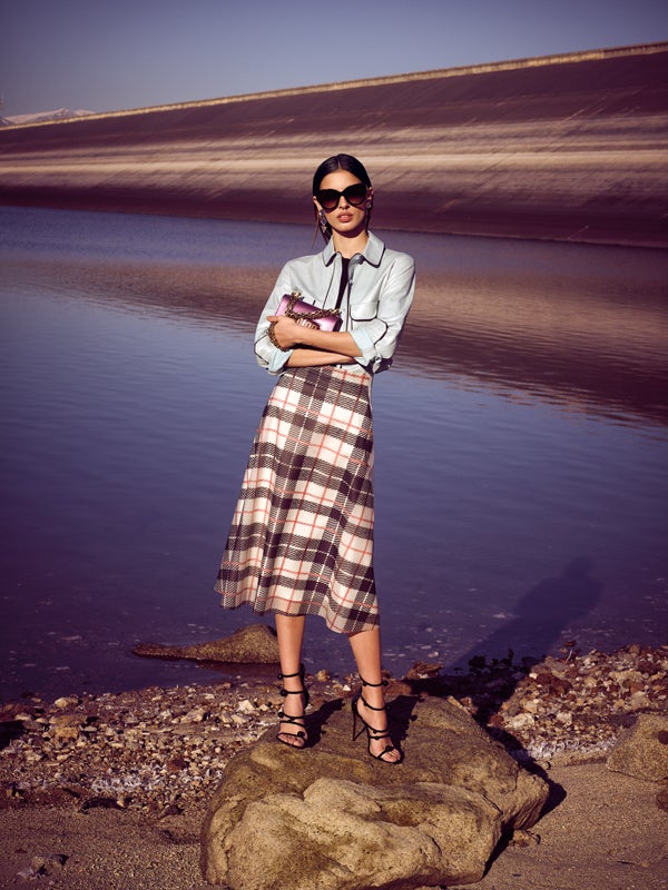 Top negro de Uterqüe con camisa de cuero, de Tod's. La falda de plástico es de Burberry para Mytheresa.com. Sandalias de Christian Louboutin; bolso de Dior; gafas de Fendi; pendientes de espejo, de Papiroga; y anillo de Suarez.