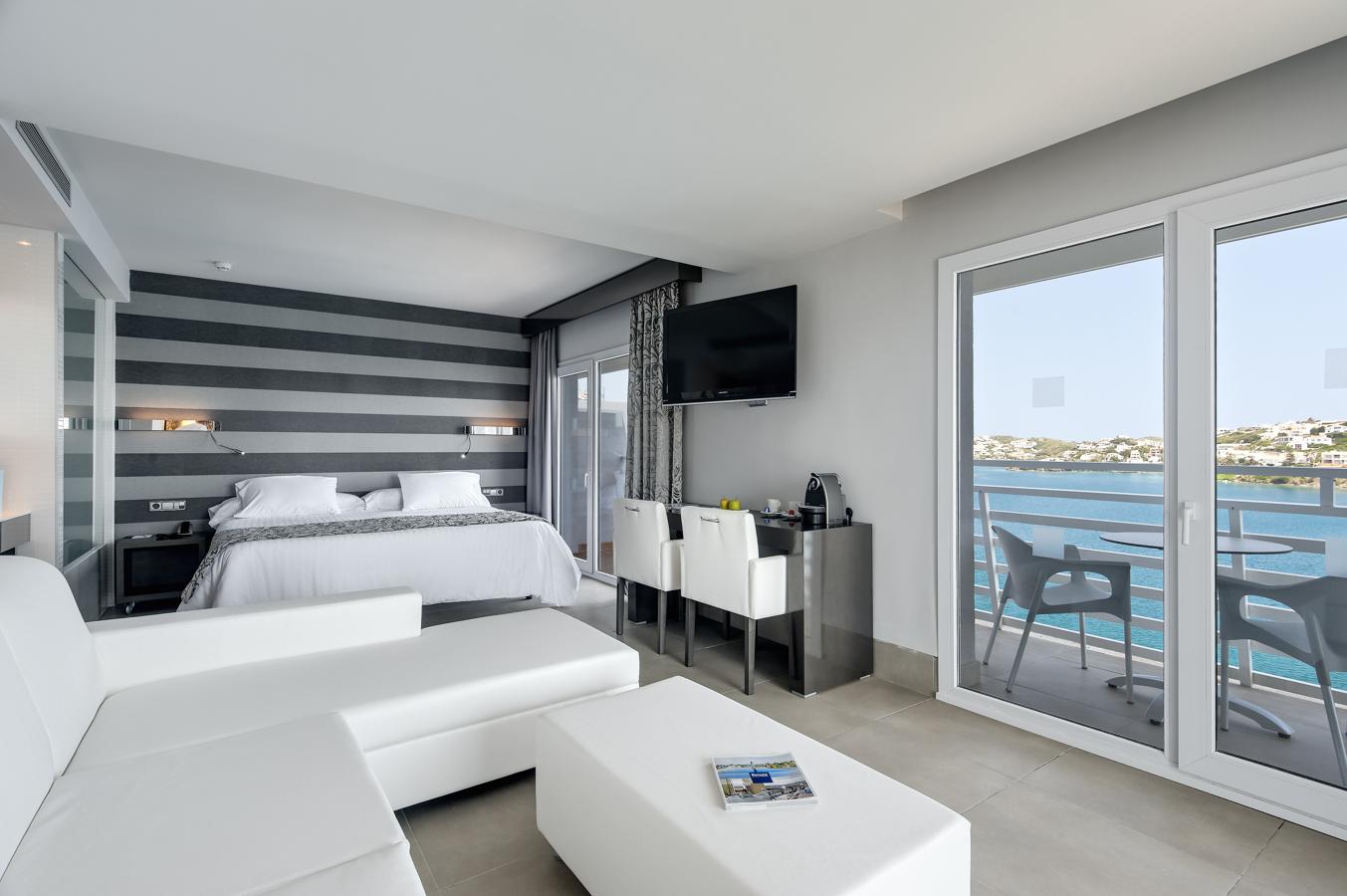 Situado en la bahía de Mahón, el Hotel Barceló Hamilton Menorca Adults Only ofrece todas las comodidades que puedas desear con un diseño moderno y unas  vistas espectaculares al mar Mediterráneo . Su concepción "Urban Beach" hace de este espacio la elección perfecta para viajes en pareja o negocios. En cuanto a su oferta gastronómica, el hotel cuenta con varios restaurantes que ofrecen una cocina mediterránea y local. Otro de sus grandes atractivos es el  Sky bar , con unas vistas 360º de Mahón, ideal para degustar uno de sus riquísimos cócteles acompañados de música chillout. Además, en el rooftop se encuentran varios jacuzzis, ideales para desconectar y tomar el sol. Más información en su  página web ..