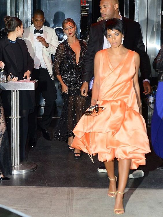 En la fotografía vemos a Solange con cara de pocos amigos, Beyoncé sonriendo como si no pasara nada y Jay Z con la ropa desencajada. ¿Por qué? El website TMZ mostró una grabación de la cámara de seguridad del ascensor del hotel Standard de Nueva York, donde se celebró la fiesta posterior a la gala del Met en 2014, en la que se ve a Solange pegando, lanzando patadas y empujando a Jay Z, y a este devolviéndole algún golpe, e pesar de que un guardaespaldas trata de evitar los agarrones.