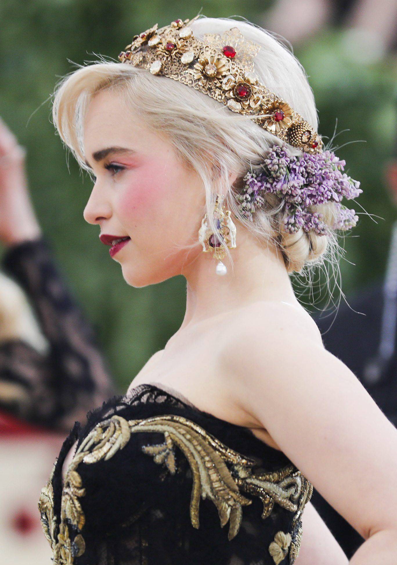 Emilia Clarke recogió su bob en un moño bajo 'messy', con mechones sueltos, pero lo más llamativo es su tocado con flores y pedrería. Con un vestido sencillo monocolor, puede ser el look de invitada perfecto.