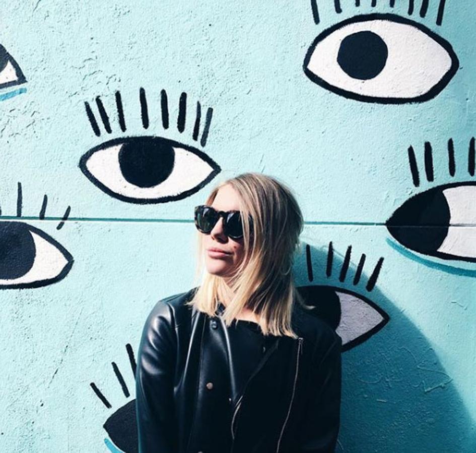 La fachada de la fotografía de Gigi Vives corresponde con la calle de la Palma, concretamente con una de las fachadas más instagrameada, de la tienda vasca de comercio justo Tom Pai. Esta fachada azul llena de ojos creada por la artista Cristina Pollesel representa la estética de la tienda y no hay influencer que se precie que no tenga su foto frente a ella.