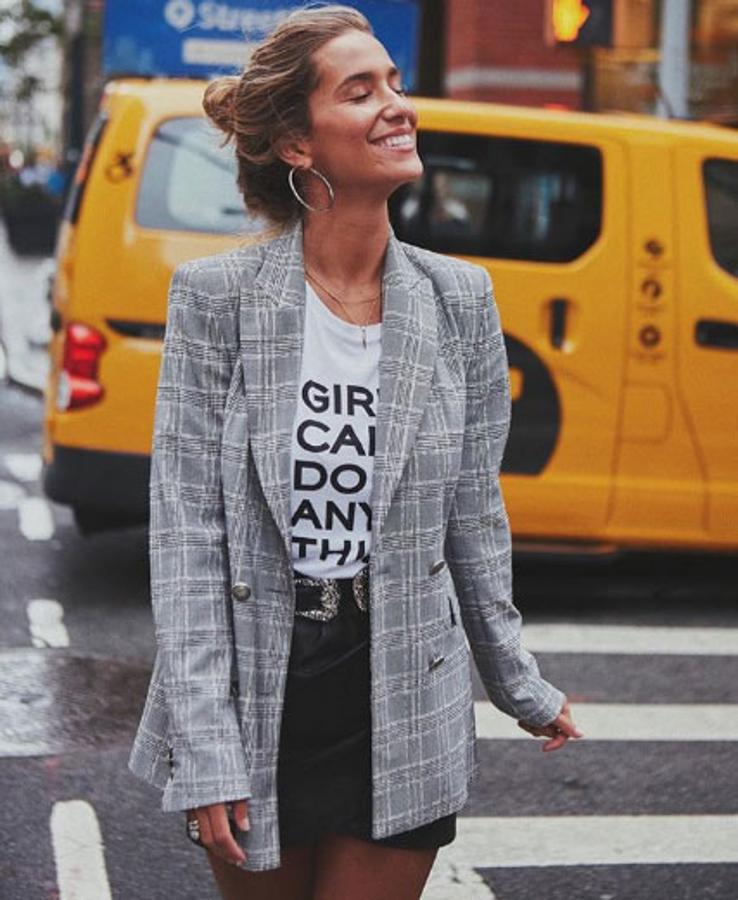 Otra opción para ir a la oficina es este 'look' con falda de polipiel, camiseta estampada y americana larga gris de cuadros.