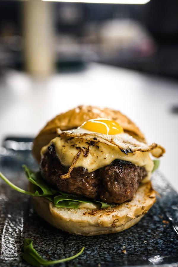 La hamburguesa Wayega, perfecta fusión del concepto japo-panamericano, se ha convertido en uno de los platos más famosos (con permiso de los niguiris y los rolls) entre los ya adeptos a Noname Bar. Carne de vaca rubia gallega y waygu, mayonesa de rábano Raifort, wasabi y cebolla caramelizada, huevo de codorniz y rúcula, todo ello entre un delicioso pan brioche, convierten a la hamburguesa de Noname Bar en, posiblemente, una de las mejores hamburguesas de Madrid. Noname Bar está en la Calle de Claudio Coello, 27, de Madrid.