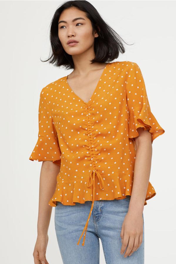 Blusa en color mostaza con lunares y cordón de ajuste, 11,99 euros.