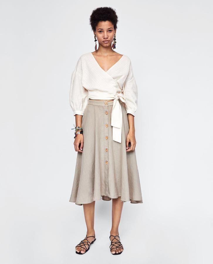 En lino rústico, color piedra, largo midi y botones delanteros. Esta falda de Zara es 'la falda', y su precio antes de las rebajas de verano es de 29.95 euros.
