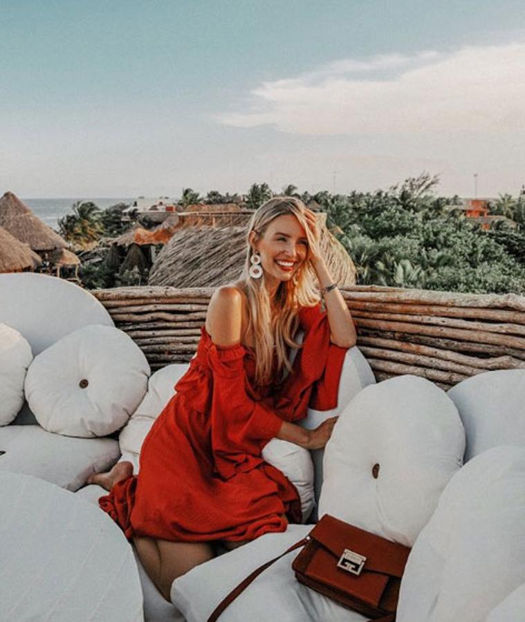 Leonie Hanne ideal con este vestido rojo con hombros descubiertos a juego con su bolso.