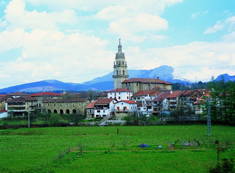 En esta fotografía se puede observar el municipio de Otxandio (Bizkaia). Rodeado de valles verdes y laderas montañosas, el conjunto arquitectónico de la Plaza Nagusia es uno de sus principales atractivos.