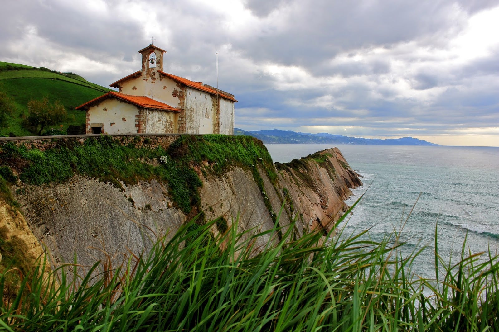 El pueblo de Zumaia (Gipuzkoa) tiene un encanto especial. En esta fotografía podemos ver la ermita de San Telmo sobre un acantilado con vistas a la playa de Itzurun. Uno de nuestros planes favoritos para este verano.