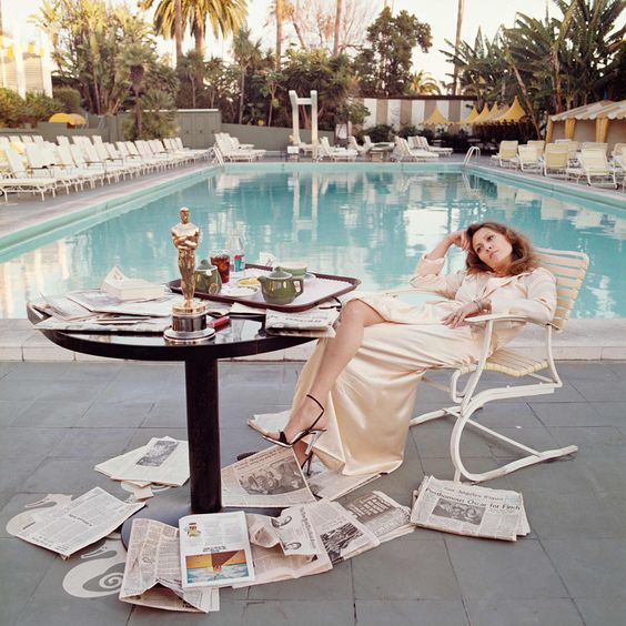 Seda y piscina. Esta es, probablemente, su foto más icónica y la más replicada. Se tomó en la piscina del hotel Beverly Hills, la mañana después de recibir el Oscar a la Mejor Actriz por su papel en “Network” (1977). El vestido camisero de seda que lleva es un 10.