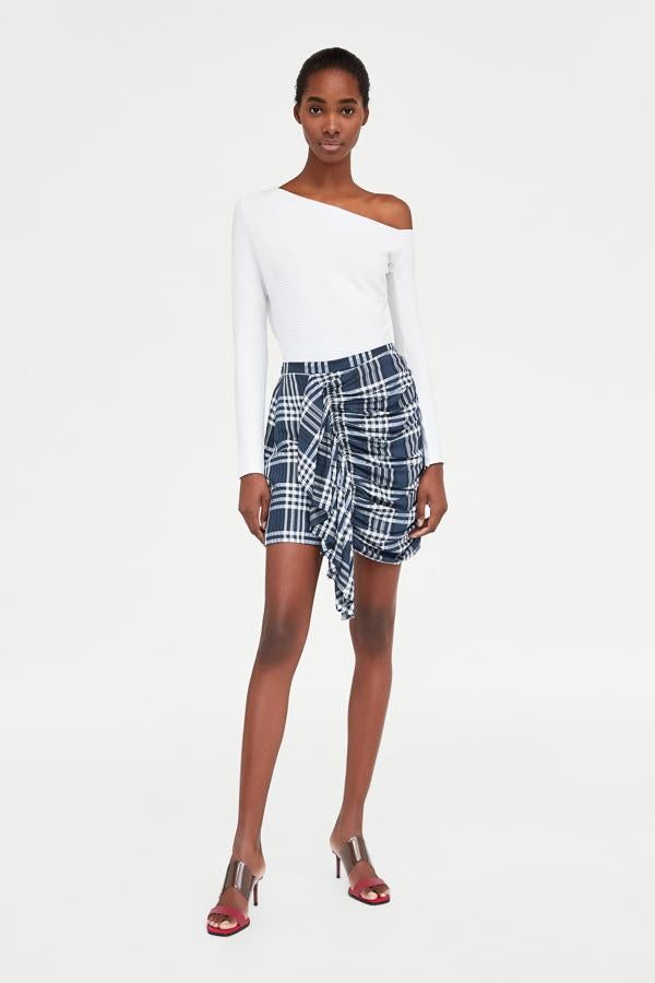 Estampado de cuadros, drapeado y detalle de cierre tipo pareo, ¿te atreves con esta falda? Su precio en las últimas rebajas de Zara pasa de 29.95 a 7.99 euros.