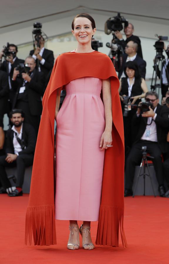 Claire Foy es la reina. Y no solo de la serie The Crown, también de la alfombra roja. La británica de 34 años demostró en la alfombra de la primera jornada del Festival de cine de Venecia que para lucir espectacular no se necesita exagerar, ni pasarse de sensual (hortera) como  Georgina Rodríguez . Vestida con un espectacular diseño de Valentino Haute Couture de esos que te enamoran al instante. La creación estaba compuesta por un vestido estructurado en color rosa chicle con una capelina roja que cubría los hombros y se extendía hasta igualar el largo del vestido.