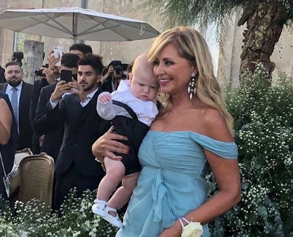 La madre de Chiara ha escogido un diseño en color azul turquesa de gasa. Los ojos se iban, por supuesto, a sus pendientes XXL. En brazos está Leone, que reconocemos que se nos cae la baba con él...