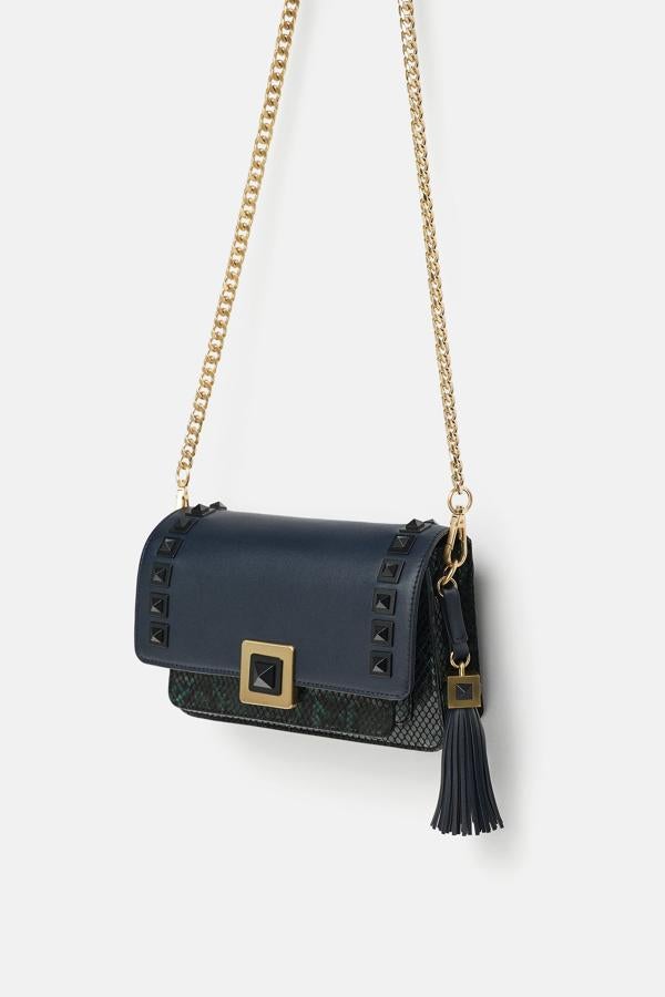 Esta bandolera de Zara no es tan minimalista, pero nos encanta el precio (39,95 euros) y la cantidad de contrastes que nos ofrece: cuatro texturas entre la initación a serpiente, las tachuelas la piel y la hebilla metálica.