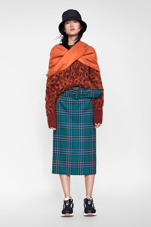 Un ejemplo perfecto de una posible mezcla de estampados y estilos la tenemos en este look de Zara con una de las faldas de cuadros más bonitas de la temporada (39,95 euros), adornada con un gran cinturón de hebillla y en un verde fantástico. La combinación con el jersey de estampado animal naranja y el pañuelo del mismo tono funciona perfectamente, aunque las deportivas son clave.