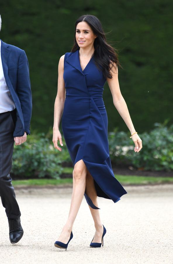 Meghan Markle continúa con los guiños a la moda australiana, esta vez eligiendo un favorecedor vestido azul 'navy' con solapa y volante delantero de Dion Lee, un modelo que ronda los 250 euros y que ha combinado con los salones BB Pumps de Manolo Blahnik (un poco más caros, 560 euros).