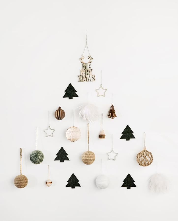 Cada año nos gusta más cómo queda un (falso) árbol de Navidad creado con adornos en tu pared. Este, que juega con los tonos blancos, verdes y la madera nos parece súper elegante y original. Las bolas cuestan 5.99 euros en Zara Home.
