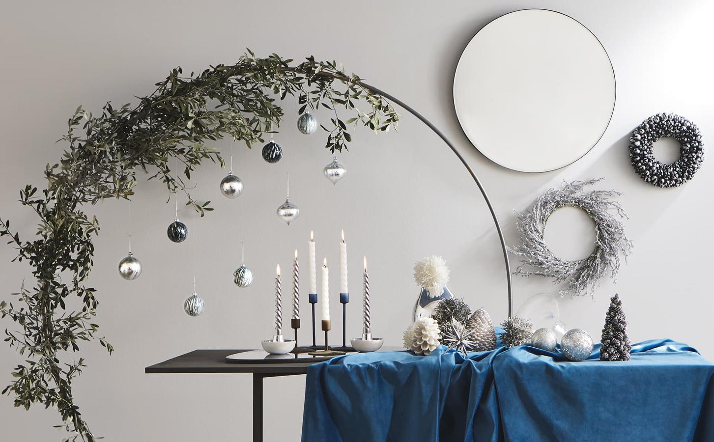 Otra idea súper orginal para poner un árbol de Navidad diferente en tu casa es este arco forrado de olivo con los adornos colocados sobre la mesa.