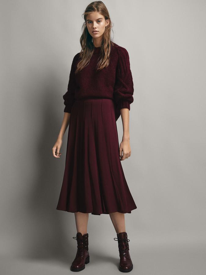 Jersey con tranzas en las mangas y acabados acanalados (65,95 euros), falda de vuelo (79,95 euros) y botón forrado de piel, también burdeos (129 euros).