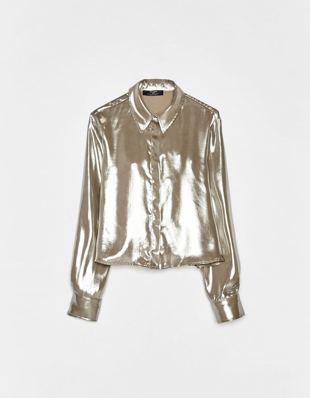 Camisa efecto metalizado para deslumbrar estas fiestas. Combínala con tus pantalones negros favoritos, unos taconazos y unos pendientes maxi dorados. En Bershka por 19,99 euros.